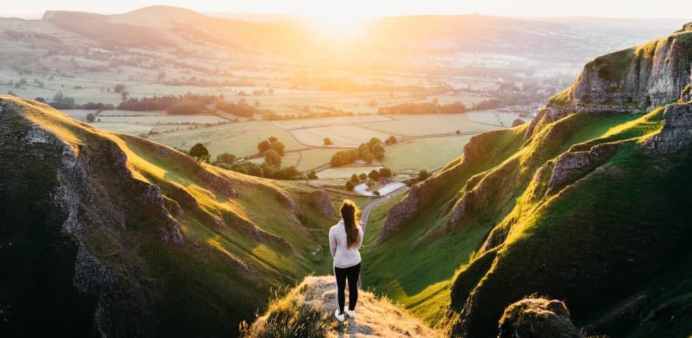 A woman looking over a large valley during sunrise, portraying potential and freedom